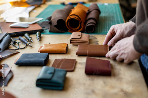 Fotografía Craftsman hands laying out leatherwork on wooden table at leather workshop