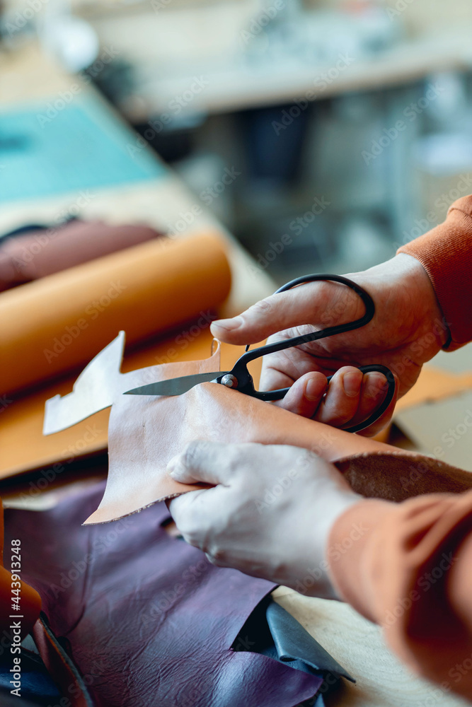 Obraz premium Craftsman cutting natural material use scissors. Working process at leather workshop