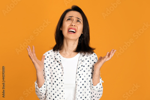 Portrait of screaming woman filled with hate on yellow background