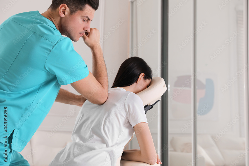 Woman receiving massage in modern chair indoors Woman receiving massage in modern chair indoors
