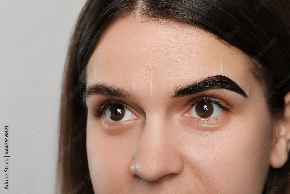 Woman during eyebrow tinting procedure on grey background, closeup Woman during eyebrow tinting procedure on grey background, closeup