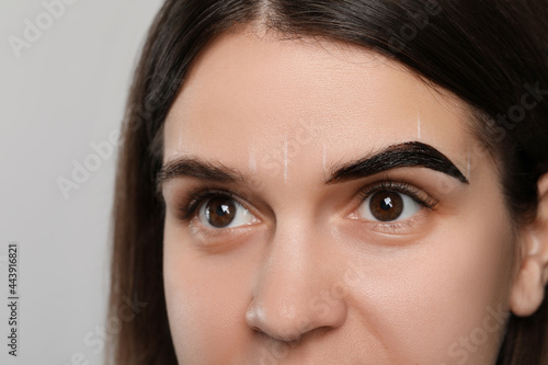Woman during eyebrow tinting procedure on grey background, closeup