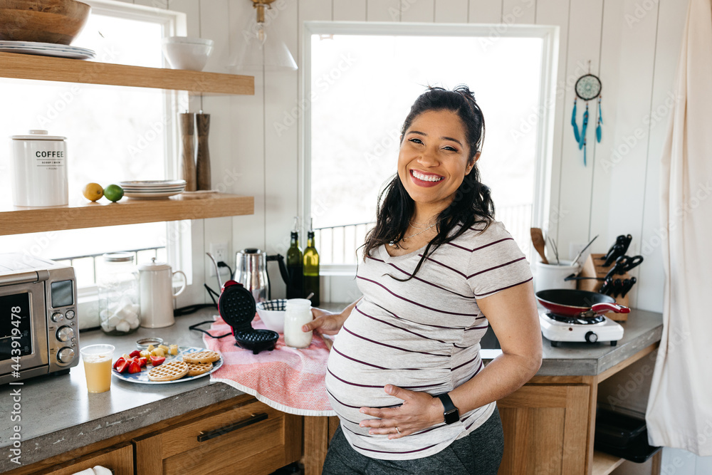 A pregnant woman cooking breakfast a small kitchen A pregnant woman cooking breakfast a small kitchen