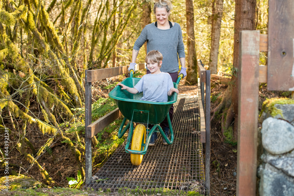 Mother and son play with a wheelbarrow in their back yard. Mother and son play with a wheelbarrow in their back yard.