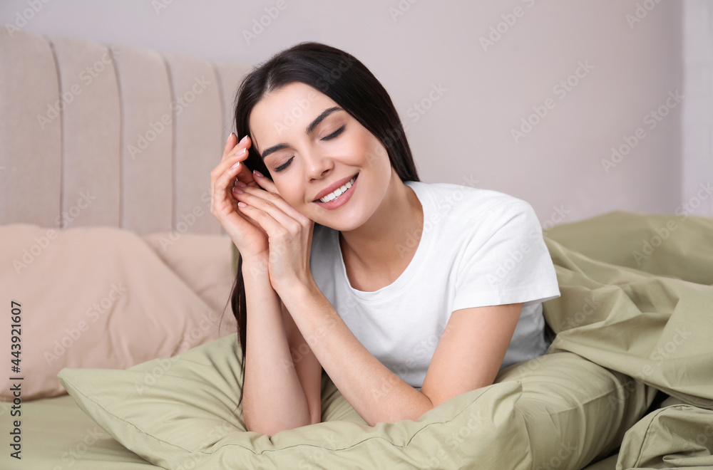 Woman lying in comfortable bed with green linens Woman lying in comfortable bed with green linens