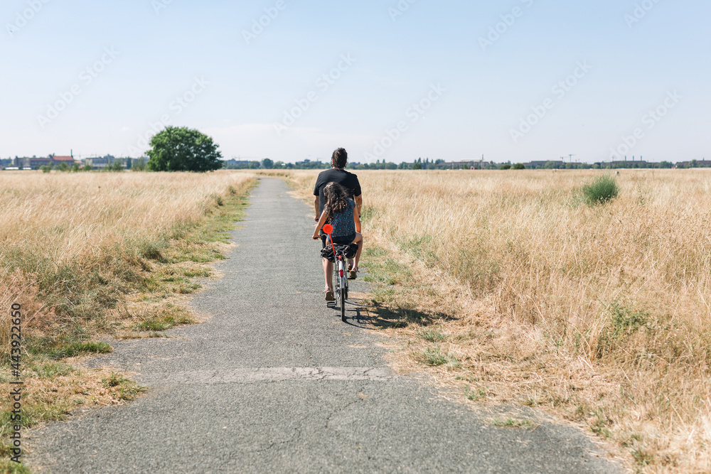 Girl and dad on a tandem bike ride in the fields Girl and dad on a tandem bike ride in the fields