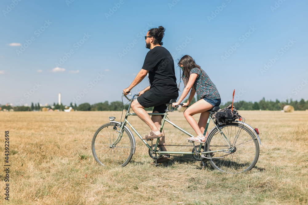 Father daughter together on a tandem bike on the field Father daughter together on a tandem bike on the field