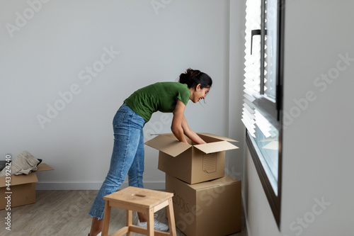 Woman unpacking moving boxes at new home photo