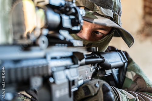 Close up side view portrait of special forces soldier or military police swat holding semi automatic rifle aiming while standing on the mission or tactical operation © Miljan Živković