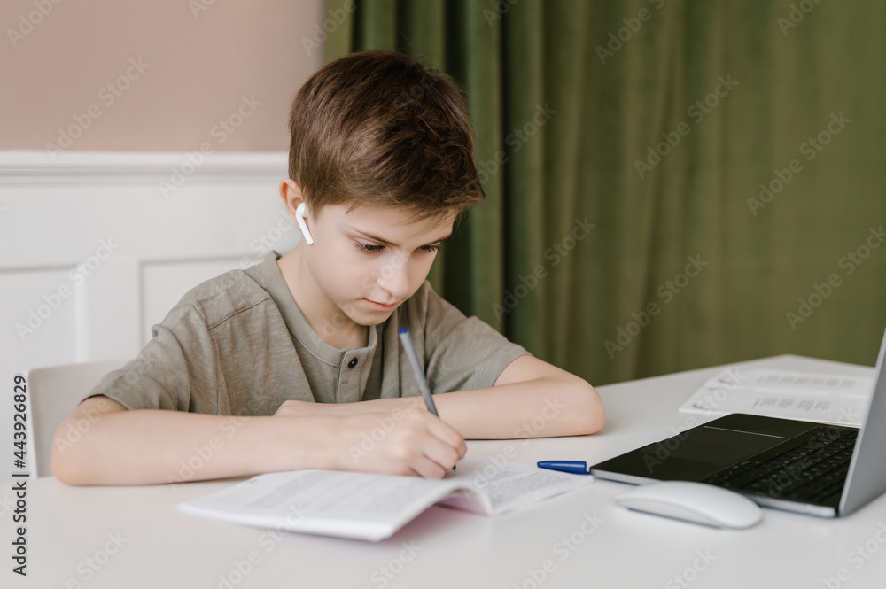 Focused boy doing homework and writing in notebook Focused boy doing homework and writing in notebook