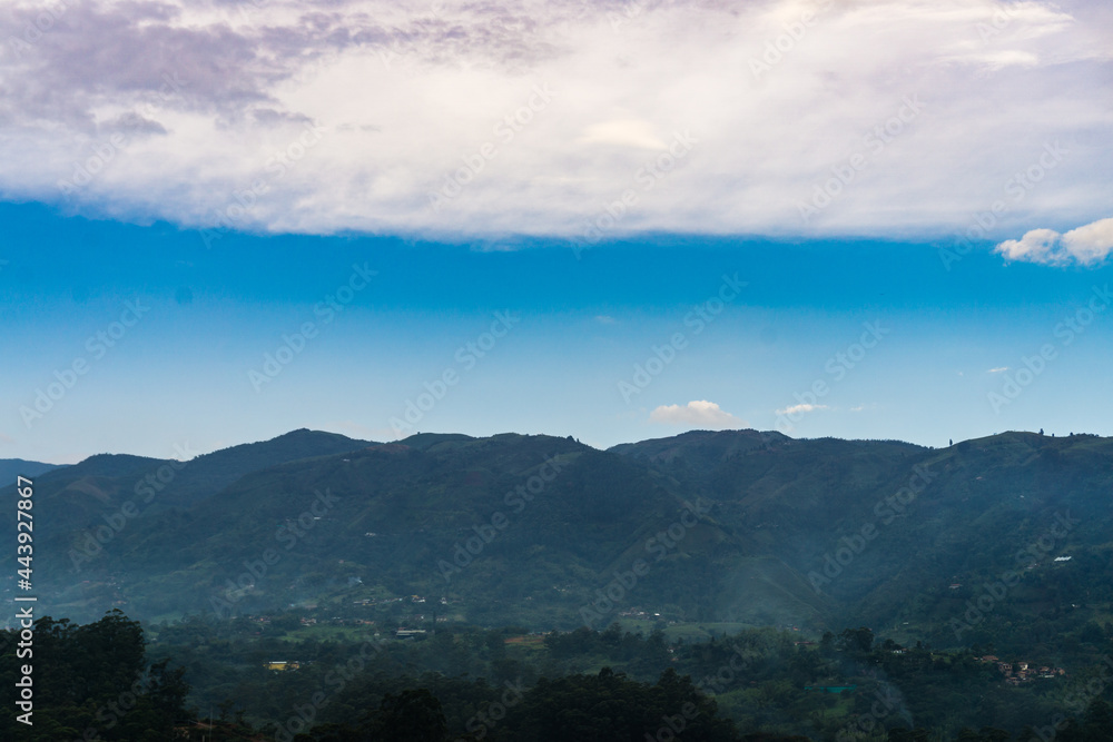 photo in three layers, dark blue mountain saw shape with a bright blue sky and a dense white cloud above