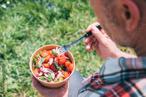 Food: Man eating a take away salad outdoors photo