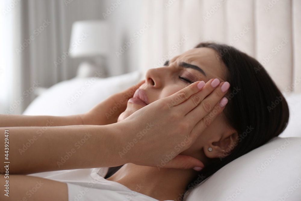 Young woman suffering from migraine in bed at home, closeup Young woman suffering from migraine in bed at home, closeup