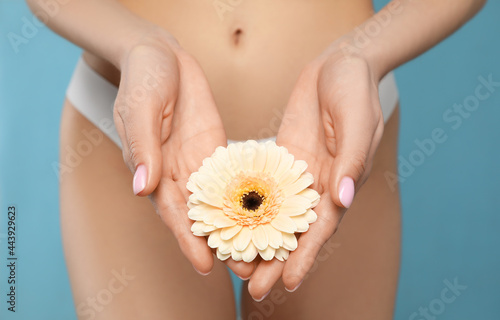 Foto Woman in white panties with gerbera flower on light blue background, closeup