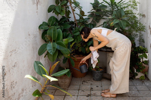 Young woman watering plants at home photo