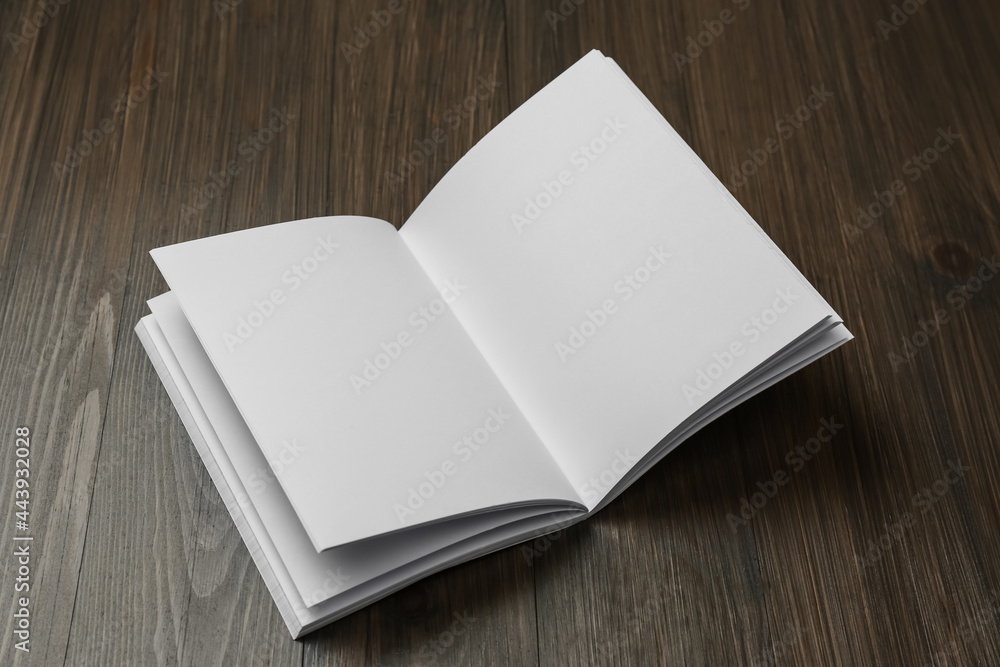 Fototapeta premium Open blank paper brochure on wooden table. Mockup for design
