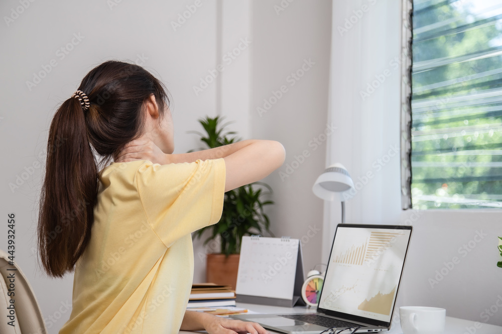 Office syndrome concept. Woman using hand to massage her neck feeling pain in neck after working on computer laptop for long time, neck fatigue, muscle pain or incorrect posture when using laptop. Office syndrome concept. Woman using hand to massage her neck feeling pain in neck after working on computer laptop for long time, neck fatigue, muscle pain or incorrect posture when using laptop.