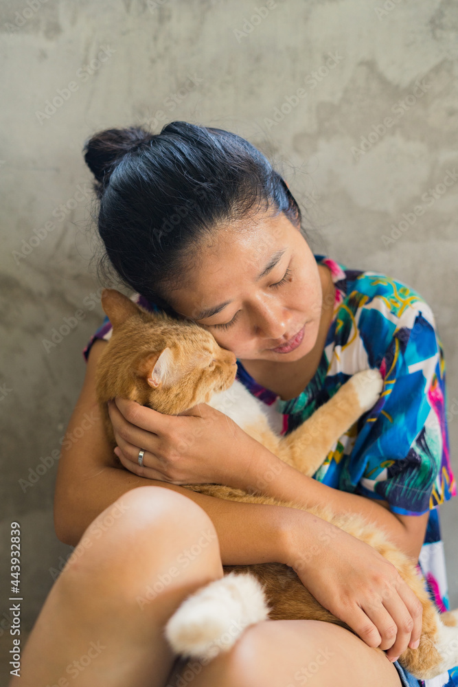 A sitting Asian woman hugging a cat A sitting Asian woman hugging a cat