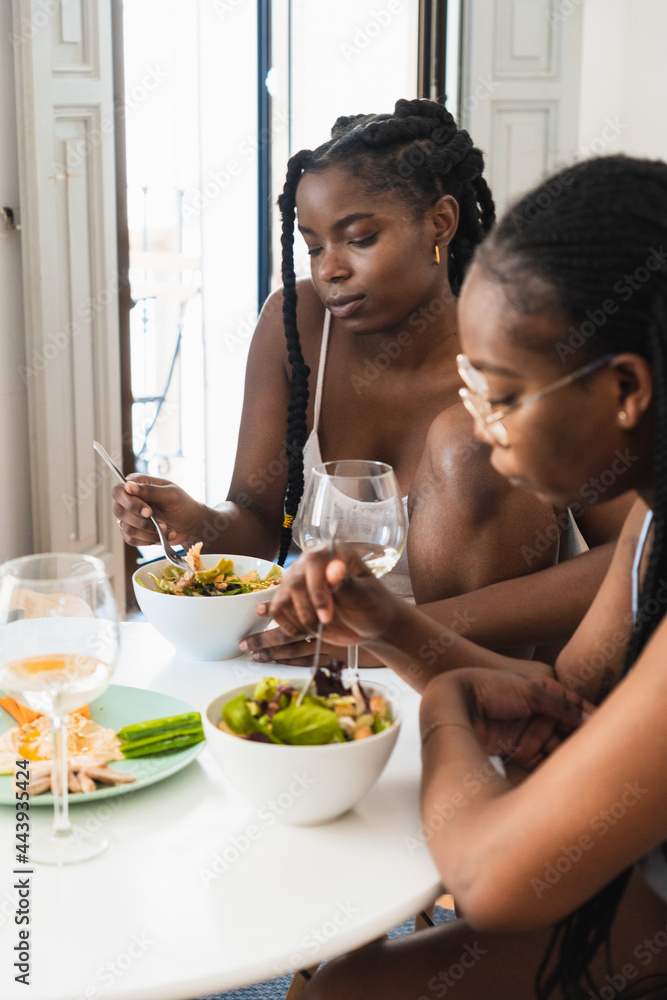Young black girlfriends having dinner with wine at home Young black girlfriends having dinner with wine at home