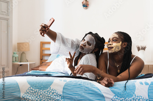 Black women in facial masks taking selfie at home photo