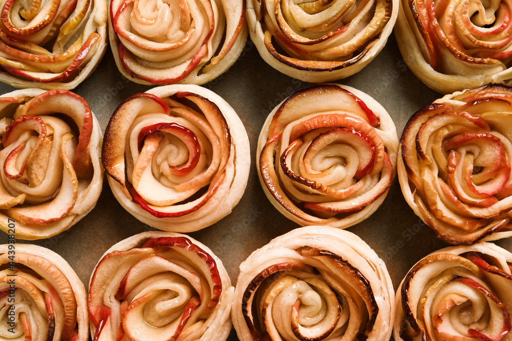Freshly baked apple roses on parchment paper, flat lay. Beautiful dessert