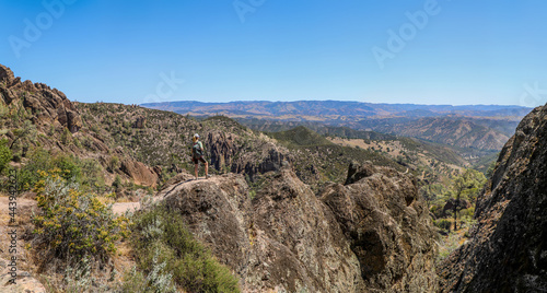 Panoramic of Woman standing on rock overlooking the beautiful landscape of Pinnacles National Park in California