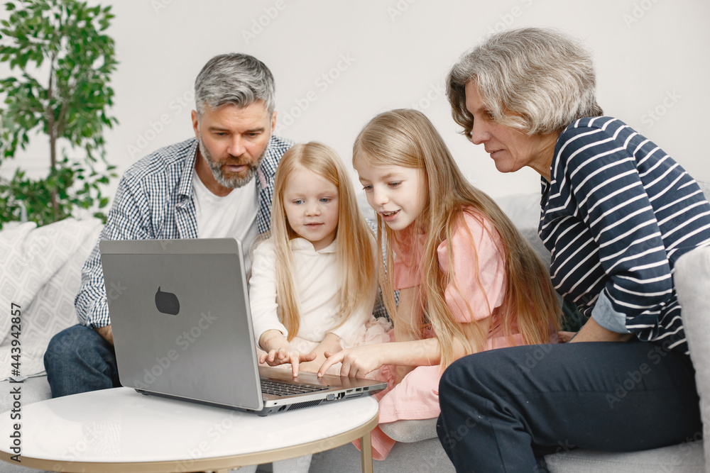Grandarents with granddaughters using laptop in the living room Grandarents with granddaughters using laptop in the living room