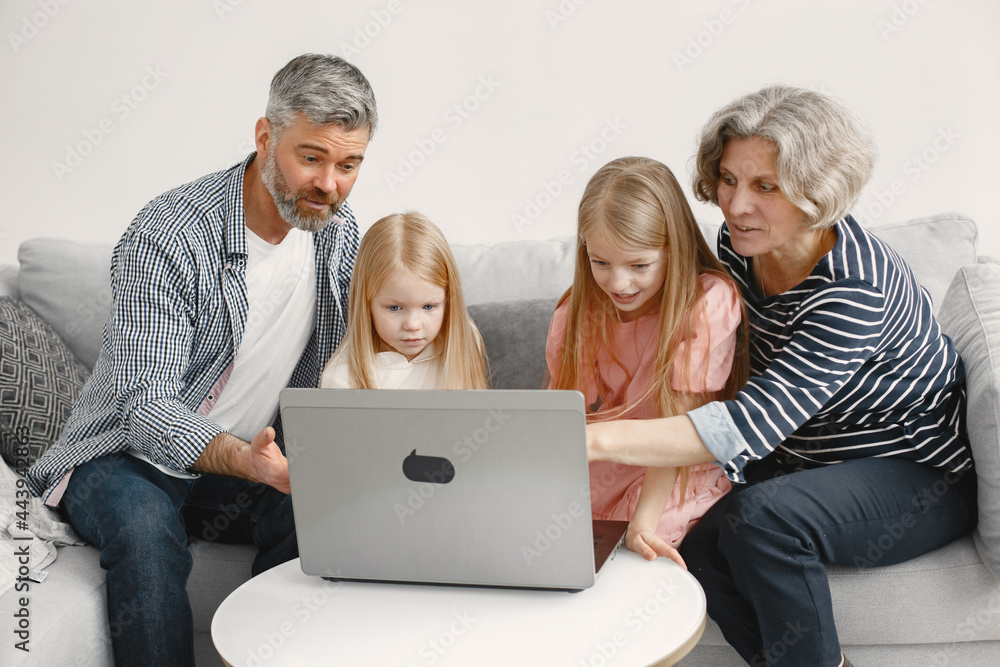 Grandarents with granddaughters using laptop in the living room Grandarents with granddaughters using laptop in the living room
