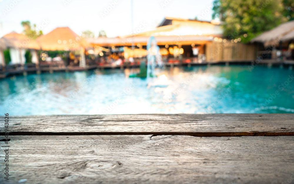 Image of wooden table in front of blurred background of pool and resturant. Image of wooden table in front of blurred background of pool and resturant.