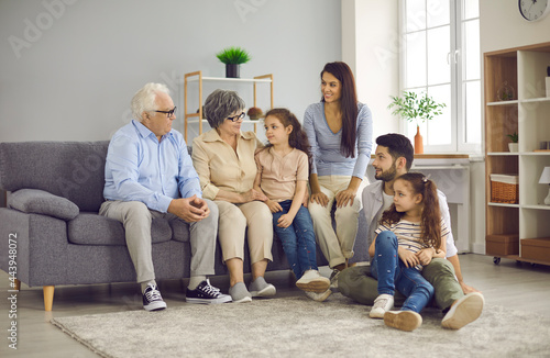 Multi-generation family sitting on sofa in living room. Portrait of a big happy family consisting of grandparents, their children and grandchildren. Family meetings and emotional communication.
