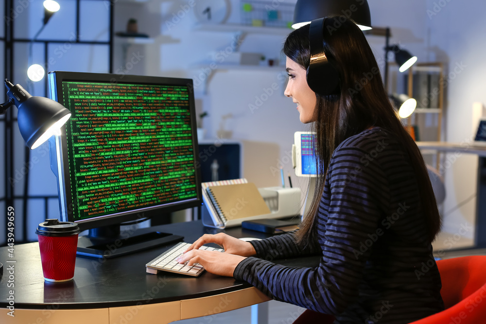 Female programmer working with computer in office at night Female programmer working with computer in office at night