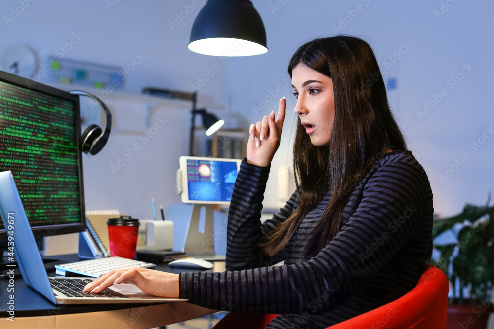 Female programmer working with laptop in office at night Female programmer working with laptop in office at night