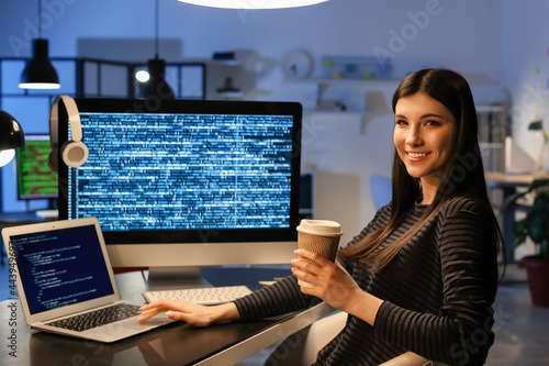Female programmer working with laptop in office at night