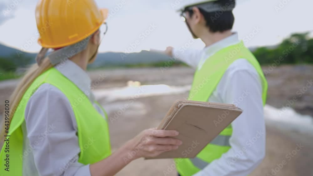 Asian workers wearing protective working gear on site of construction field, analyzing possibility from designed structure digital blueprint inside portable wireless tablet, teamwork coordinator plan Asian workers wearing protective working gear on site of construction field, analyzing possibility from designed structure digital blueprint inside portable wireless tablet, teamwork coordinator plan