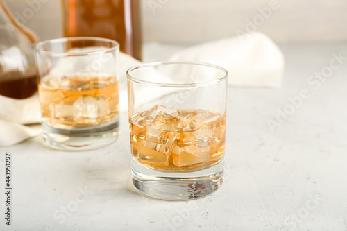 Glasses of cold whiskey on light background