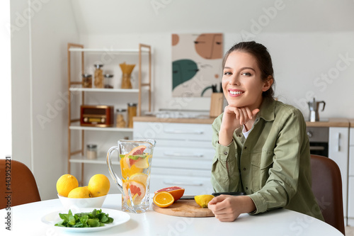 Young woman making fresh lemonade at home