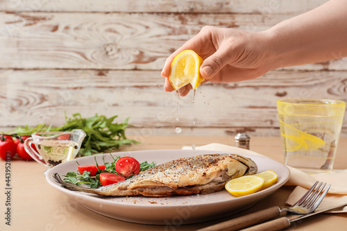 Картината върху платно Woman squeezing lemon juice onto fried dorado on plate, closeup