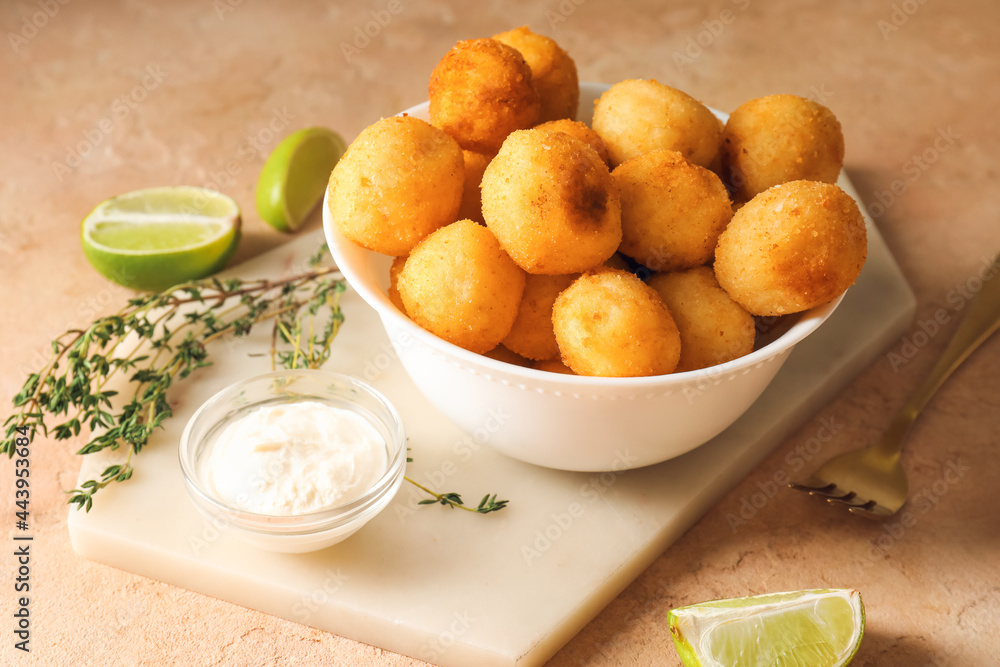 Bowl with fried potato balls and sauce on color background Bowl with fried potato balls and sauce on color background