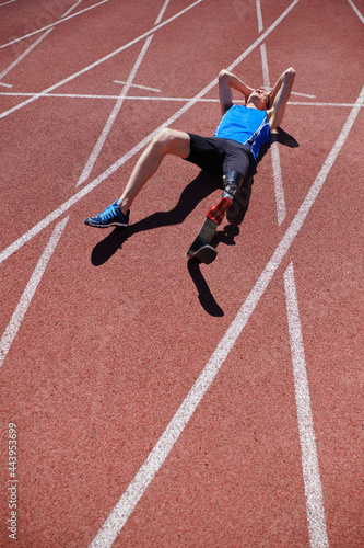 Man with artificial leg laying on the stadium track © sata_production