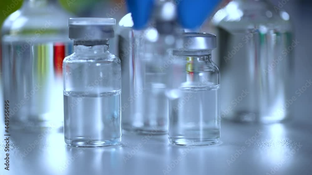 Close-up of scientist slowly put down a vial of vaccine or chemical on a research table with many other vial lying around Close-up of scientist slowly put down a vial of vaccine or chemical on a research table with many other vial lying around