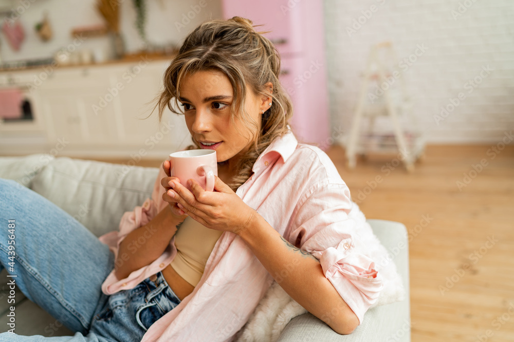 Graceful woman in casual clothes resting un sofa in cozy living room. Holding cup of tea. Graceful woman in casual clothes resting un sofa in cozy living room. Holding cup of tea.