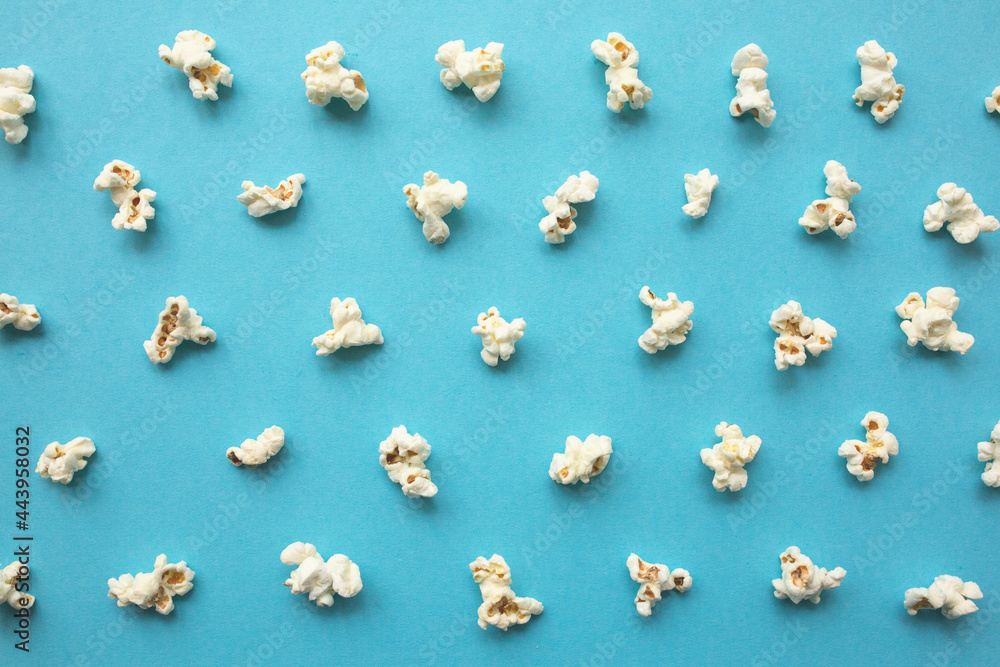 Fototapeta premium Popcorn scattered on blue background. Popcorn pattern. top view.