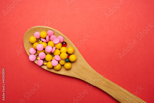 pills in a spoon on a red background top view antibiotics medicine