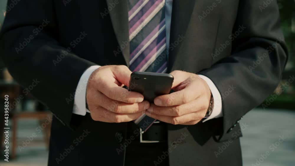 4k Male reading phone message or downloading an app for his mobile phone.Smiling Middle aged businessman in luxury clothing in financial district in metropolitan city using mobile phone for texting 4k Male reading phone message or downloading an app for his mobile phone.Smiling Middle aged businessman in luxury clothing in financial district in metropolitan city using mobile phone for texting