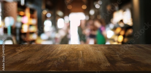 Empty wooden table in front of abstract blurred background of coffee shop . 