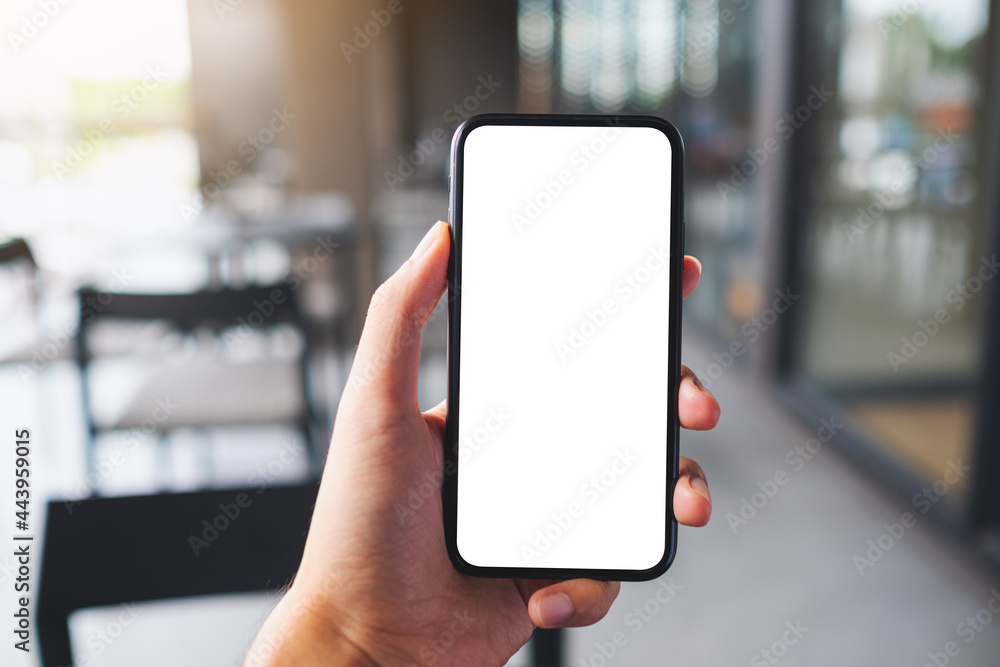 Mockup image of a man holding black mobile phone with blank white screen in cafe