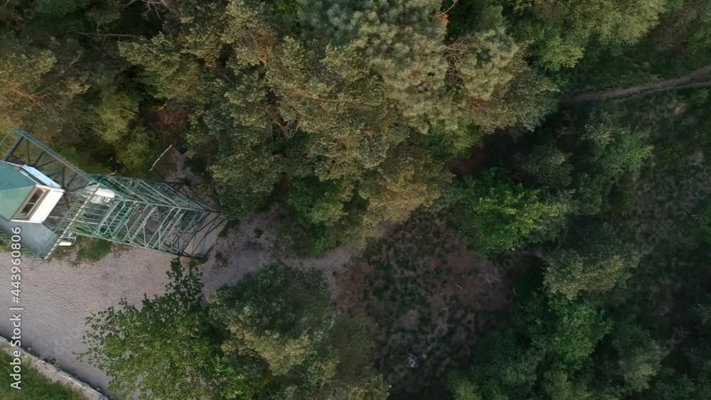 Flyover old watchtower and dirt road surrounded by dense forest, top down aerial view Flyover old watchtower and dirt road surrounded by dense forest, top down aerial view