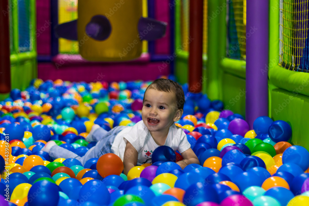 Obraz premium cute and happy little girl laughing and playing in an indoor playground in a shopping mall in Dubai, United Arab Emirates.