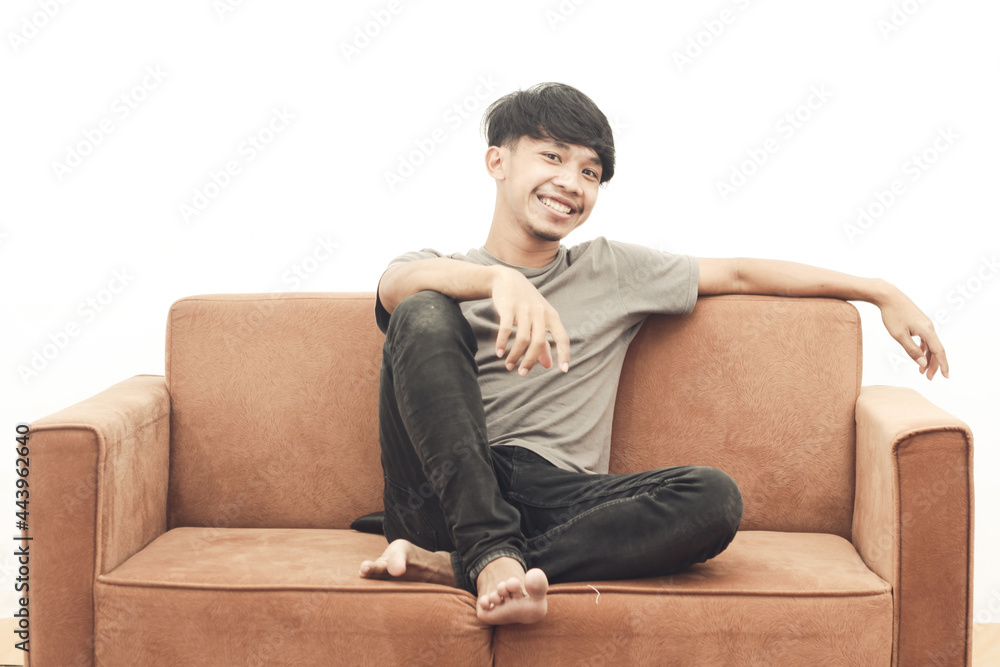 portrait of asian youth wearing gray t-shirt sitting on the sofa laughing happily portrait of asian youth wearing gray t-shirt sitting on the sofa laughing happily