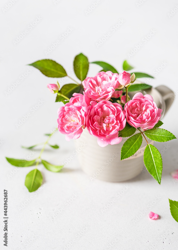 Obraz premium Beautiful bouquet of pink mini roses in a small espresso cup. Still life with summer flowers. Copy space.